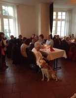 10 Gäste sitzen am Tisch. Auf dem Boden sitzt ein Blindenführhund.
